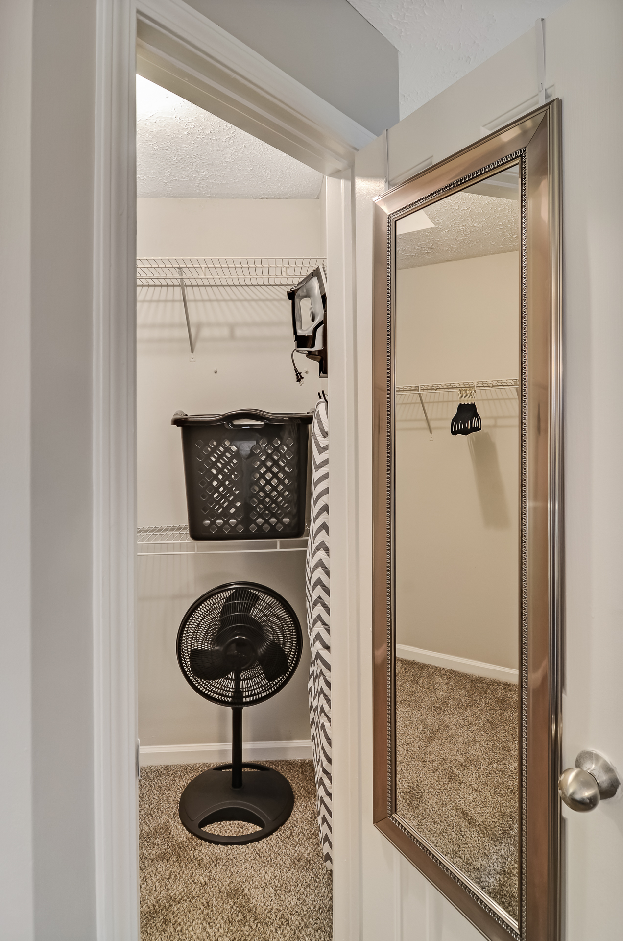 Spacious bedroom walk in closet with fan and ironing board